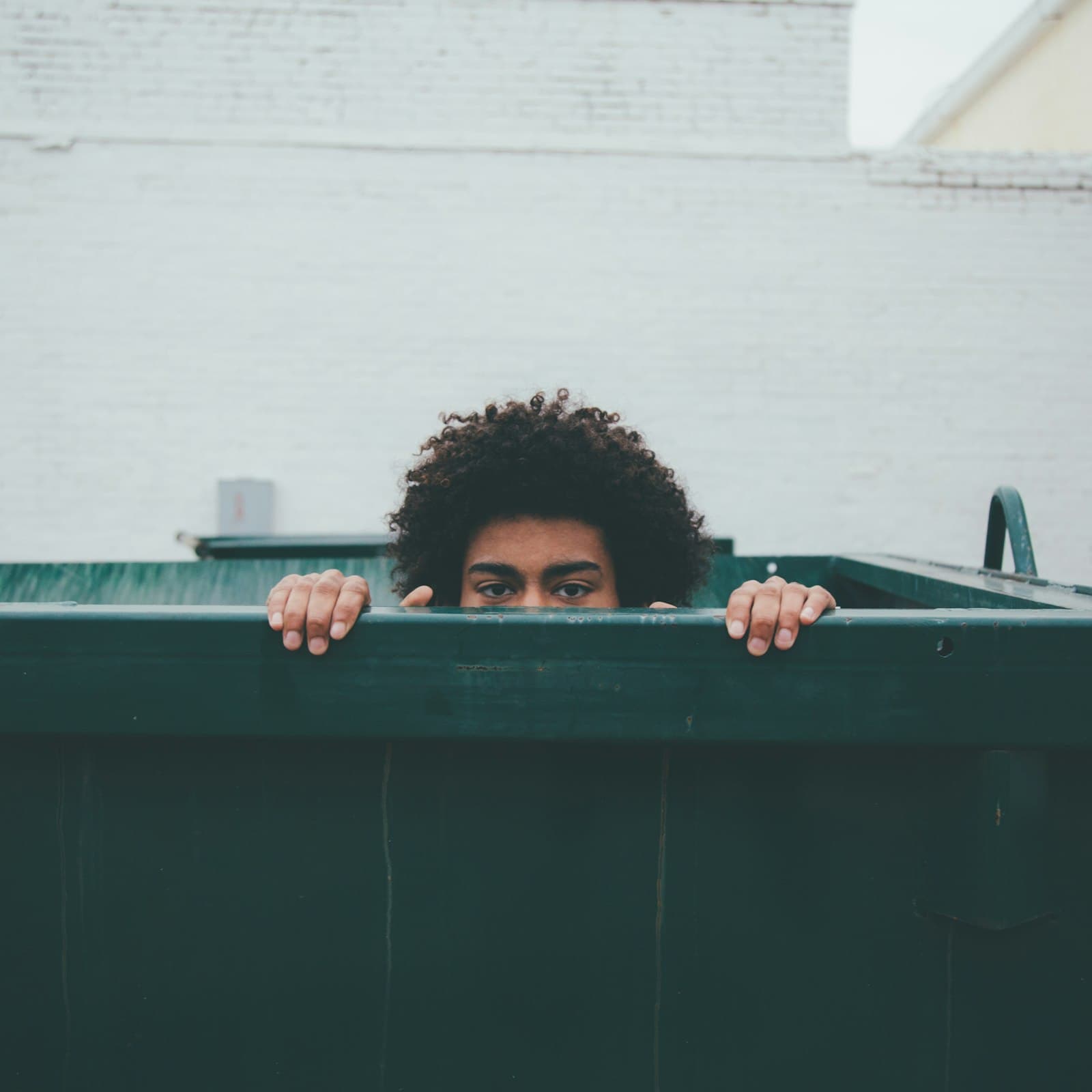 Person peeking over the edge of a green container